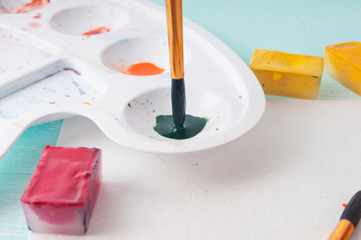 A man takes a brush watercolor paint before painting