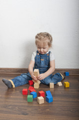 Little cute girl playing with a wooden constructor