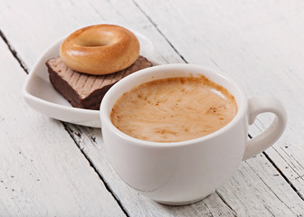 Cup of coffee and delicious baked cookies on old wooden background.