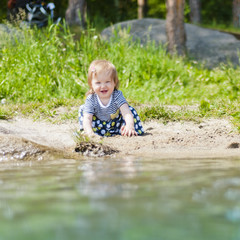 Little girl playing on the river bank