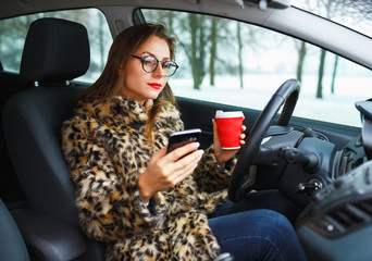 Businesswoman in a fur coat with red lips sending a text message