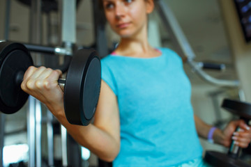 Fototapeta na wymiar Woman with dumbbells in the gym doing sport exercises