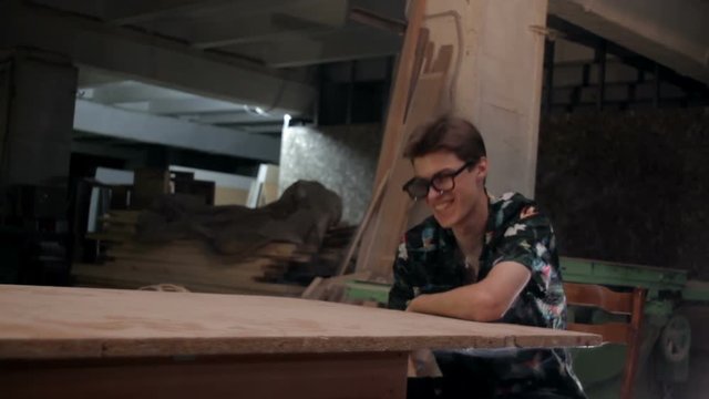 Man with glasses sits at a table and smiling