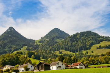 traditional Swiss landscape with wooden houses and the Alps