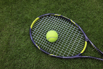 Tennis ball and racket on green grass background