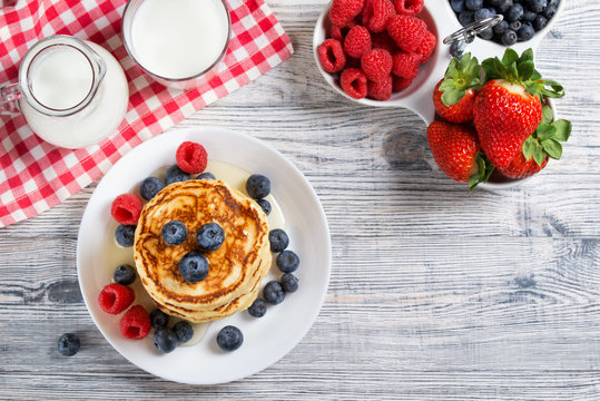 Stack of pancakes with fresh blueberry, raspberry and honey, milk and fresh berries, healthy breakfast concept, top view