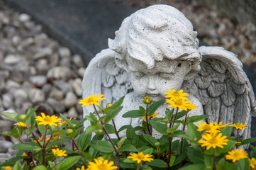 angel and yellow flowers on a grave