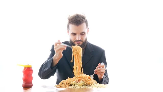 Funny businessman eating pasta on the table. Overeating and greedy consumerism concept, studio isolated on white background.