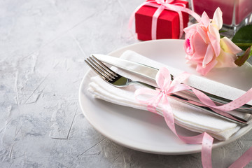 Valentines day table setting. Plate silverware heart decorations flower.