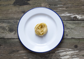 
Tagliatelle italian pasta served on plate on rustic wooden background,