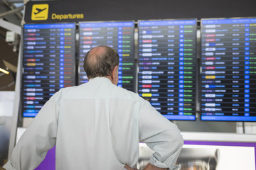 Male passenger at the airport, looking at the flight information board