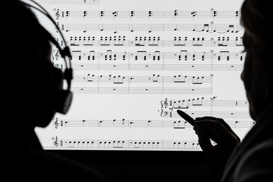 Two people working on a musical score using computer notation software. Not a real score, notes randomly drawn in by the photographer.