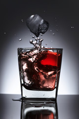 Glass of whiskey with falling ice on a black background