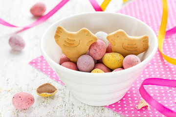 Easter chocolate candy eggs and bird cookies in bowl