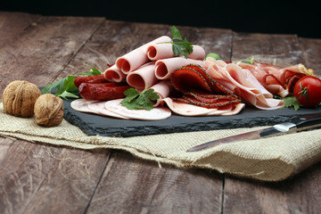 Food tray with delicious salami, pieces of sliced ham, sausage, tomatoes, salad and vegetable - Meat platter with selection
