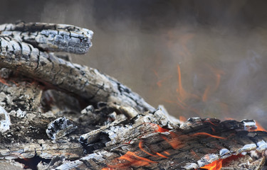 background with smoldering charred wood and red flames of fire