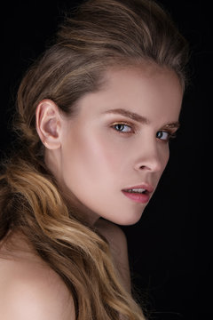 Close-up portrait of beautiful young woman. Fashion shiny highlighter, sexy gloss lips. Healthy skin, dark eyebrows and wavy hairstyle.