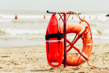 Ring buoy and can of lifeguard on the beach with sea with people - obrazy, fototapety, plakaty