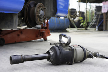 Wrench machine against car wich has tire needs to fix on background