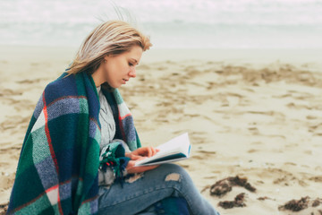 Fototapeta na wymiar A girl reads a book on the beach