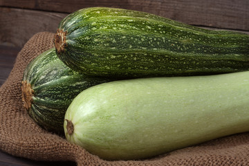 green zucchini and courgette on sackcloth wooden background