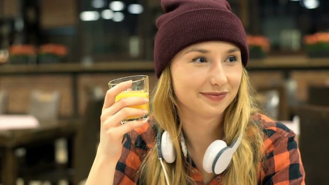 Happy, hipster girl drinking juice and looking thoughtful, steadycam shot
