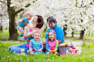 Naklejka na ściany i meble Family with children enjoying picnic in spring park