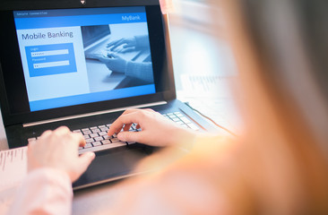 Close up of woman hands using on line banking on laptop computer logging in to a bank account typing password. Business, financial and secure payment concept. 