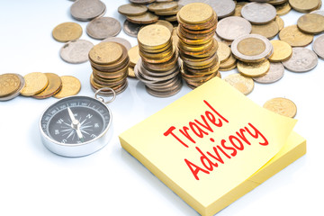 Coins, compass and text on sticky note with travel and financial concept