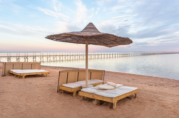 Sun lounger under the beach umbrella with view at the sea coast