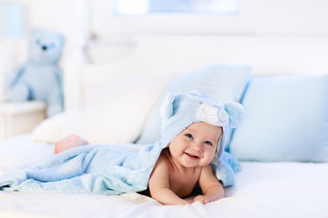 Baby in towel after bath in bed