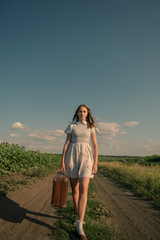 Obraz premium Cute girl goes on a dirt road in field