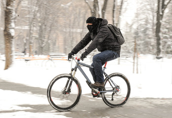 A man rides a bicycle in snowy weather