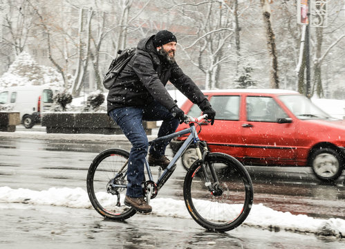 A man rides a bicycle in snowy weather