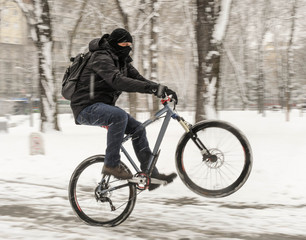 A man rides a bicycle in snowy weather