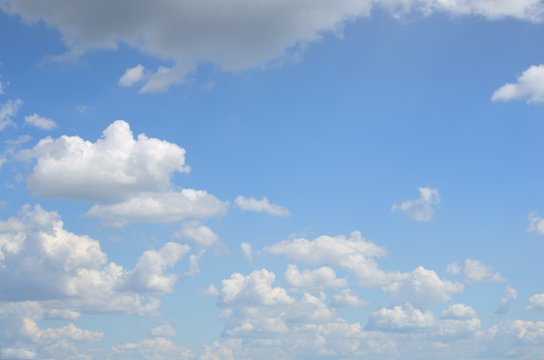 Blue sky with many of white and gray clouds above the water on summer day as a natural background for your text or picture; cloudscape running to horizon