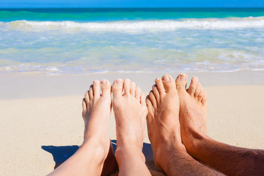Couples feet on the beach. Tropical beach holiday concept. 