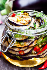 Grilled  sliced eggplant with chili in glass jar on rustic table