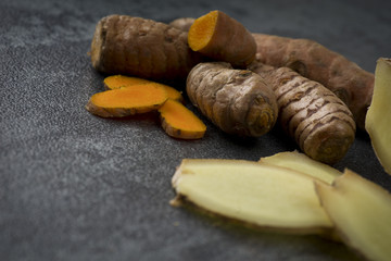 turmeric slices and ginger root sliced on gray background