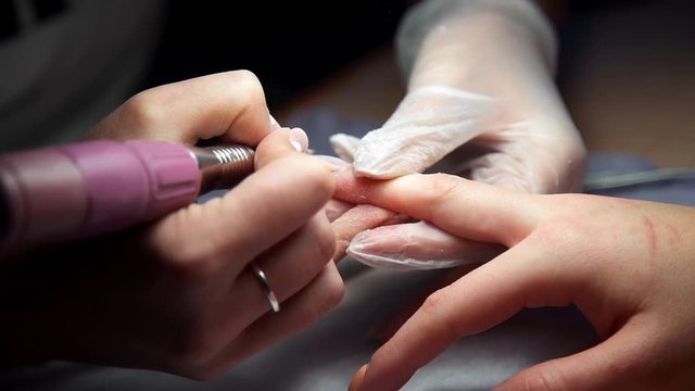 Master of manicure makes hardware manicure, woman comes to the manicure salon, nail care, business in beauty