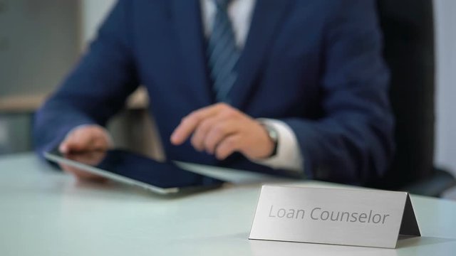Male loan counselor working on tablet pc, helping clients with debt settlement