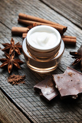 Fototapeta na wymiar Chocolate skin treatment. Cosmetic jar with lotion, cocoa, anise, cinnamon sticks.