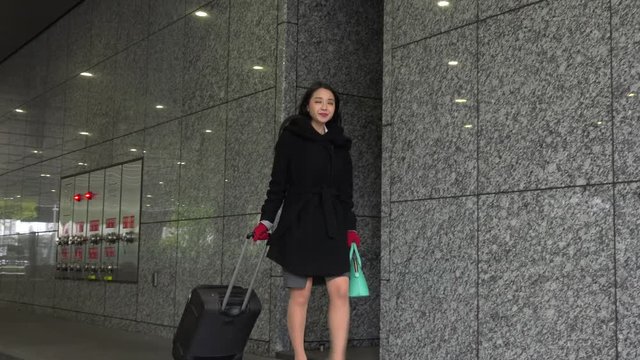 Happy Japanese female manager calling taxi during business trip in airport terminal. Asian businesswoman, confident girl, busy woman looking for a cab near office buildings in winter