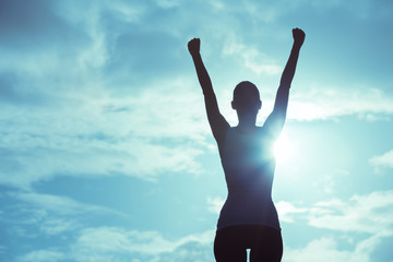 Female winning concept. Strong and confident woman raising her hands up in the air. 