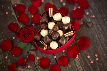 Red roses and chocolate pralines in heart shaped gift box.