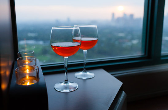 Romantic hotel setting. Pair of wine glasses, candle light and a beautiful city view. 
