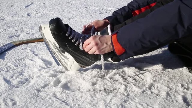 Man tying hockey skate before ice skating.