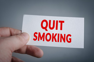 Quit smoking card in hand with dark background