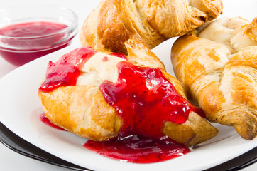 Croissant with strawberry jam on white plate