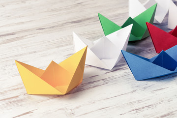 Business leadership concept with white and color paper boats on 